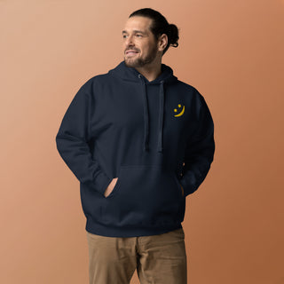 Man wearing The Happy Channel® Smile Unisex Premium Hoodie in navy with gold embroidered Smile