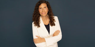 Lisa Eve smiling in a cream blazer, celebrating turning 50