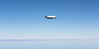 Blimp floating in sky with negative space