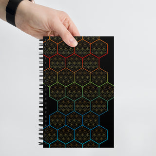 A man holding a spiral notebook with hexagonal and flower of life designs