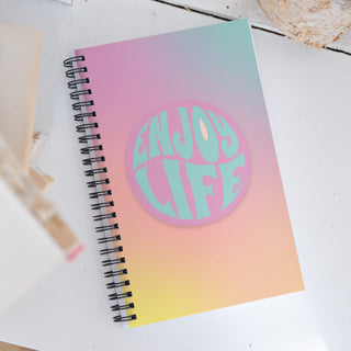 Notebook with 'Enjoy Life' sticker on a white surface