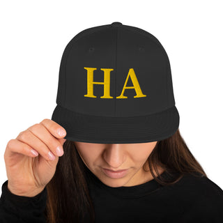 Woman wearing The Happy Channel® HA Snapback Hat with gold embroidery