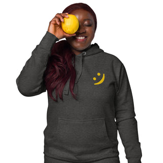 Woman wearing The Happy Channel® Smile Unisex Premium Hoodie in charcoal with gold embroidered Smile