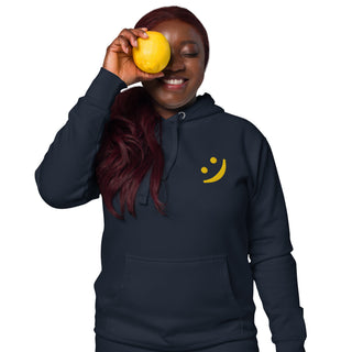 Woman wearing The Happy Channel® Smile Unisex Premium Hoodie in navy with gold embroidered Smile